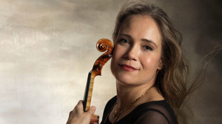 Leila Josefowicz poses with her violin in front of a background