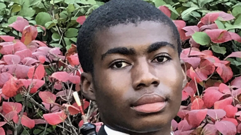 Zachary Allen stands outside in front of a tree