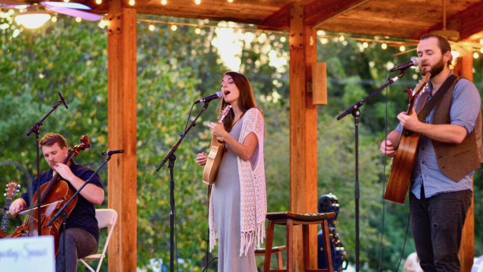 cellist, singer and guitarist under a gazebo