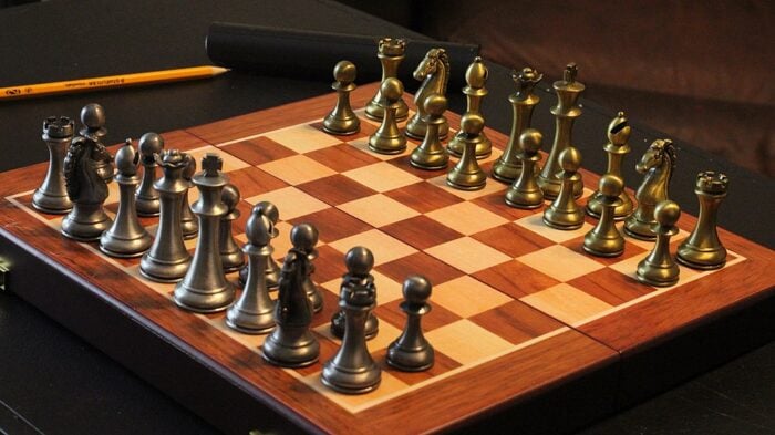 metal chess pieces on a wooden board