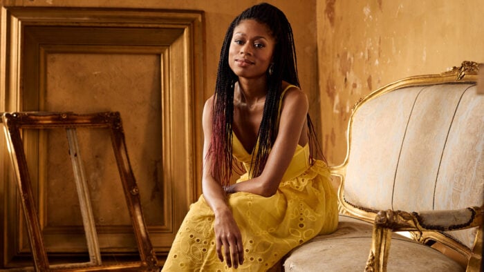 Isata Kanneh Mason, wearing gold, poses on a settee