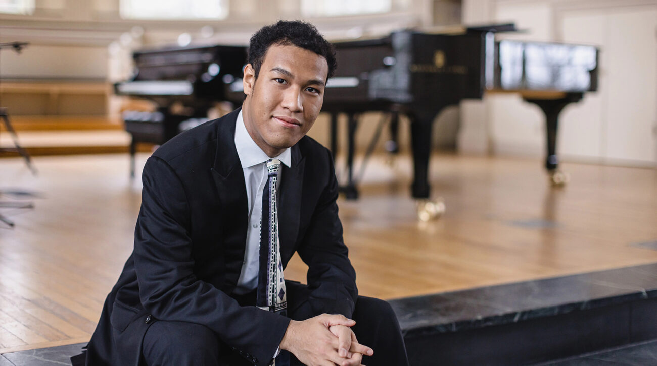 Clayton Stephenson sits with a piano in the background