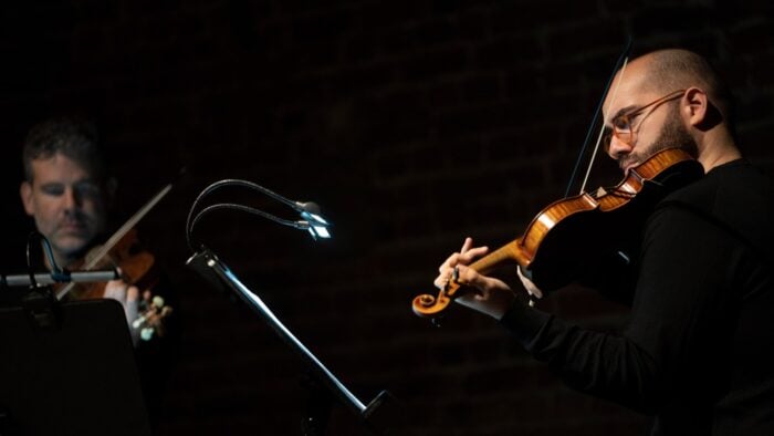 Two male violinists perform from music on music stands