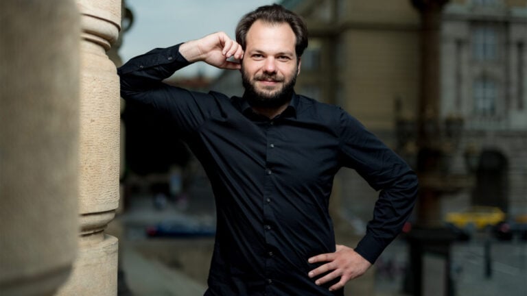 portrait of Petr Popelka leaning against a stone building