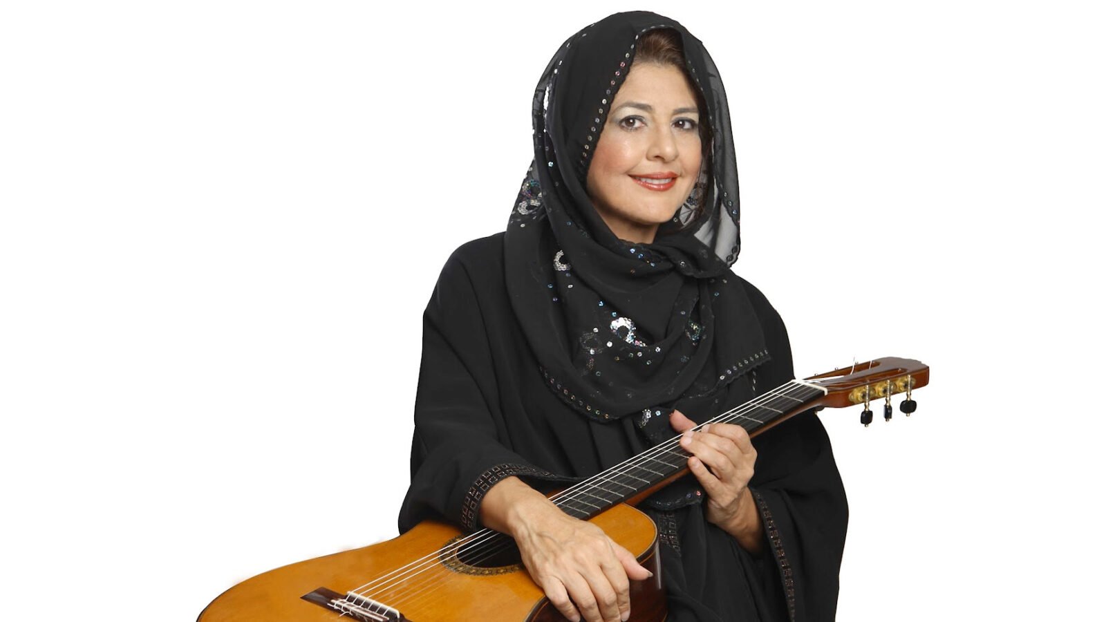 Lily Afshar, in a traditional black veil and dress, smiles with a guitar