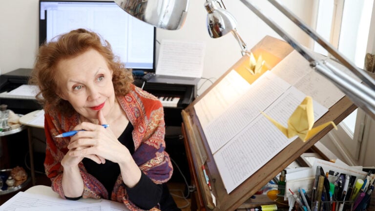 Kaija Saariaho works thoughtfully at a desk