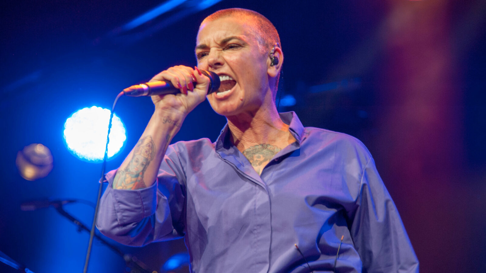 Sinéad O'Connor sings passionately into a microphone onstage