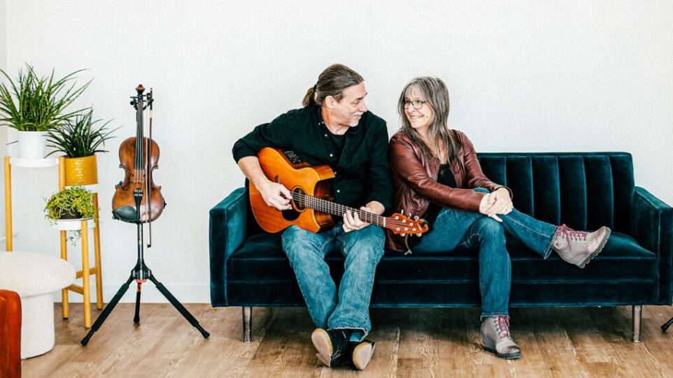 man with guitar and woman together on sofa