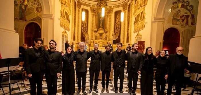 11 people dressed in concert black in a an ornate monastery