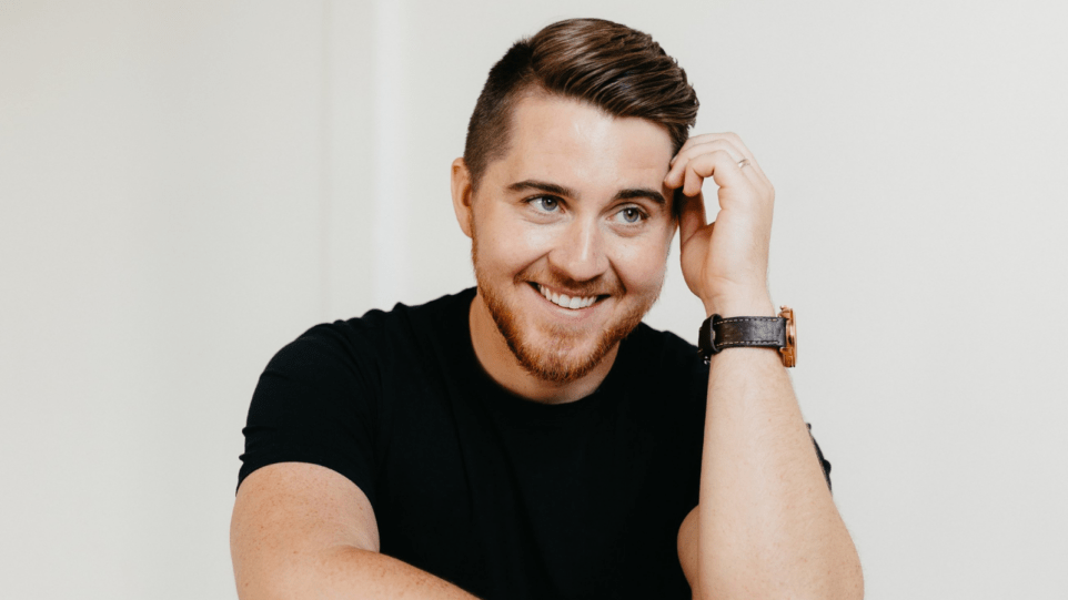 Portrait of Jack Swanson in black t-shirt, smiling and looking towards the upper right corner; white background.