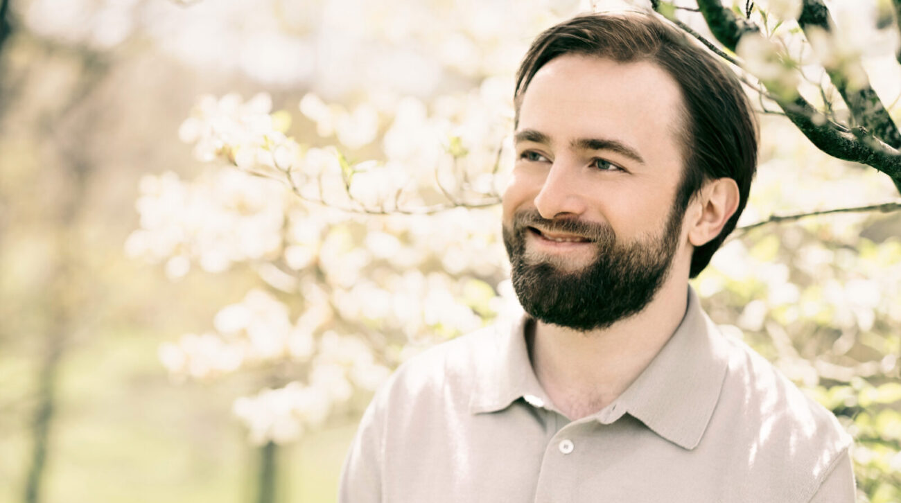 Daniil Trifonov smiles while under a sunlit tree