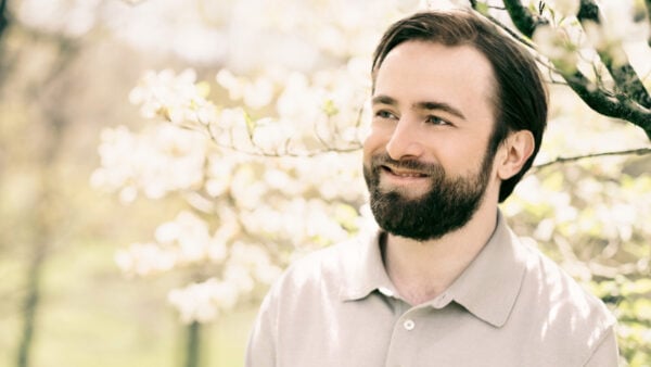 Daniil Trifonov smiles while under a sunlit tree