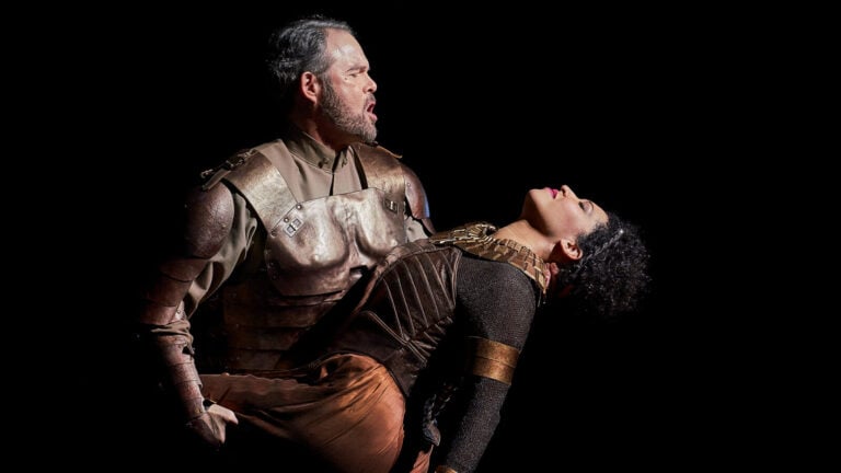An anguished Gerald Finley, dressed in armor as Antony, holds the limp body of Julia Bullock as Cleopatra in a performance of Antony and Cleopatra