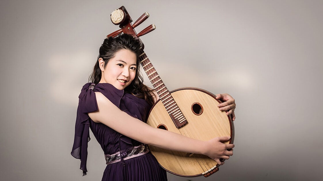 Tzu-Tsen Wu poses holding a ruan, a traditional Chinese stringed instrument resembling a banjo