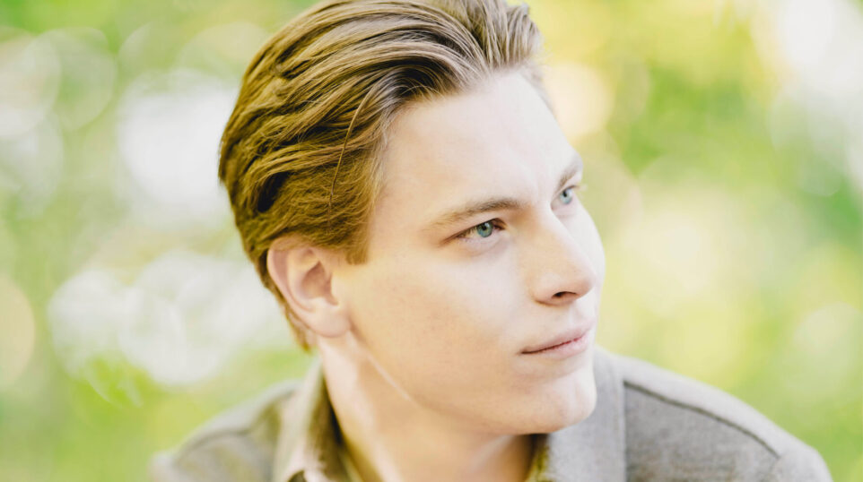 Klaus Mäkelä stares into the distance in a green outdoor scene