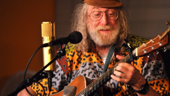 Man in front of microphone plays guitar