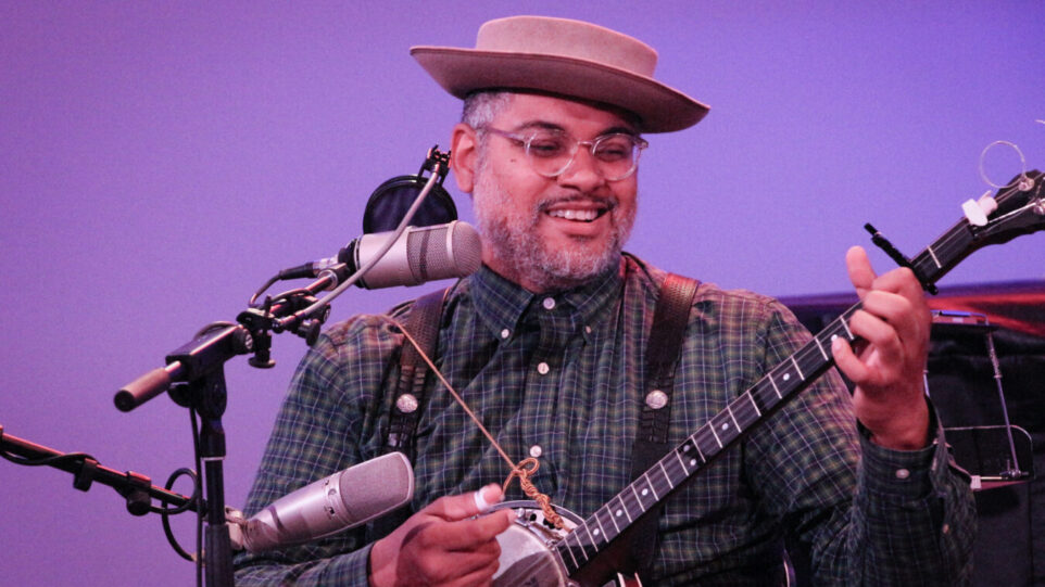 smiling man in hat plays banjo