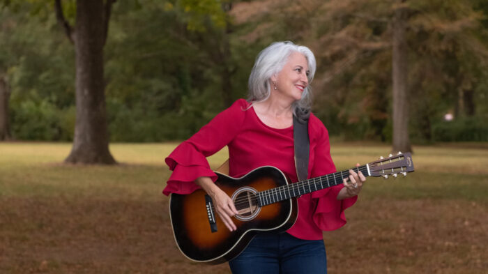 woman holding guitar looking to her left