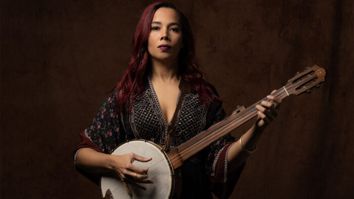 Rhiannon Giddens stares solemnly while playing a banjo