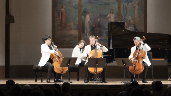 Popper's Requiem, Op. 66 A group of four men, all in white, are playing a piece of chamber music. The group consists of a 3 cellists and a pianist.