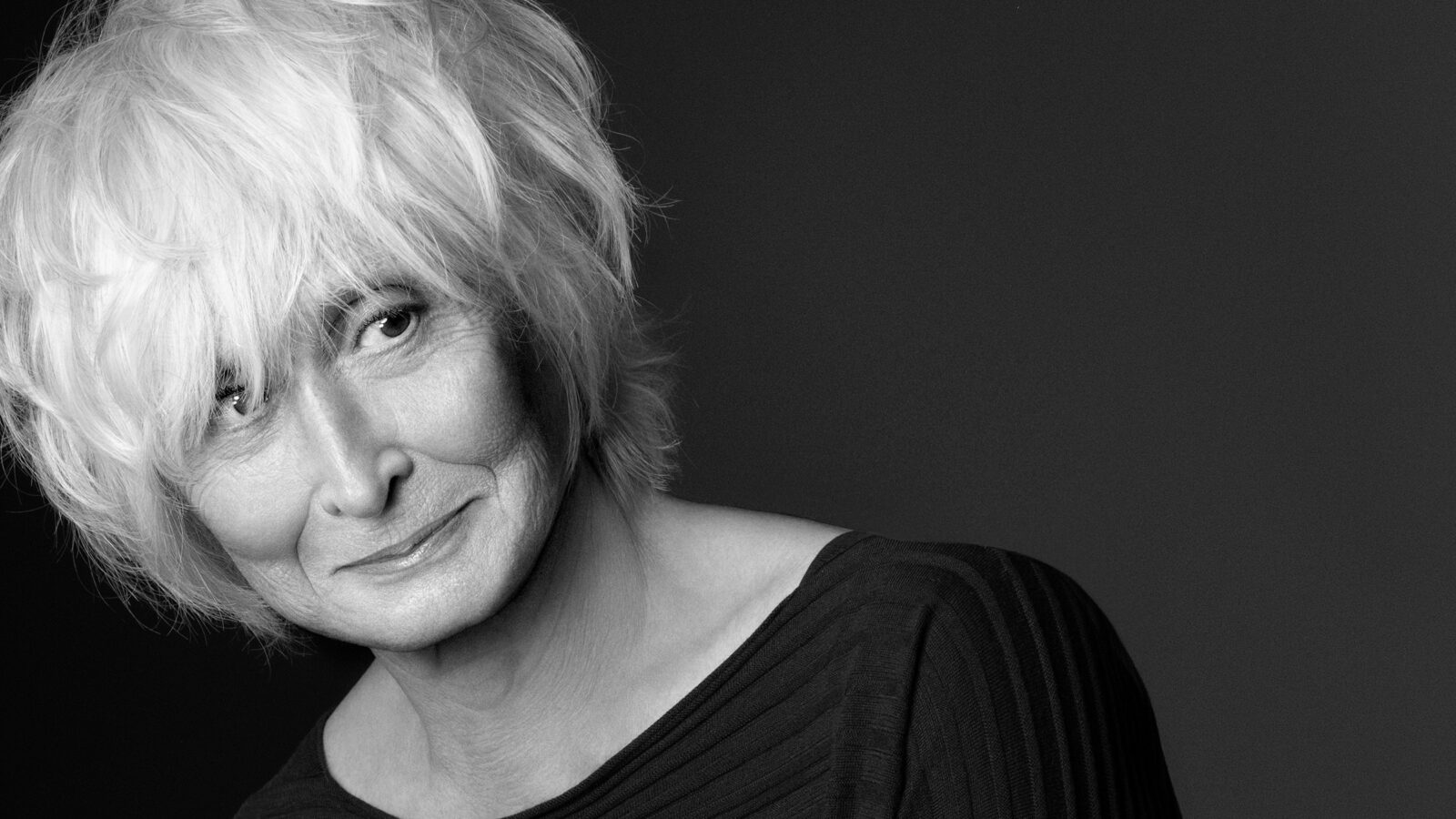 black and white photo of Twyla Tharp with a wry half smile