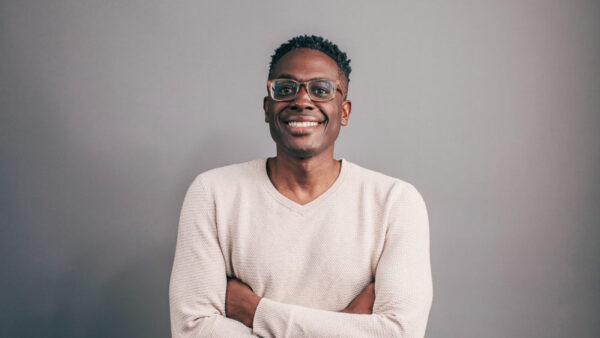 May 6 - May 10, 2024 Headshot of composer Shawn E. Okpebholo, smiling with arms crossed in front of a grey background