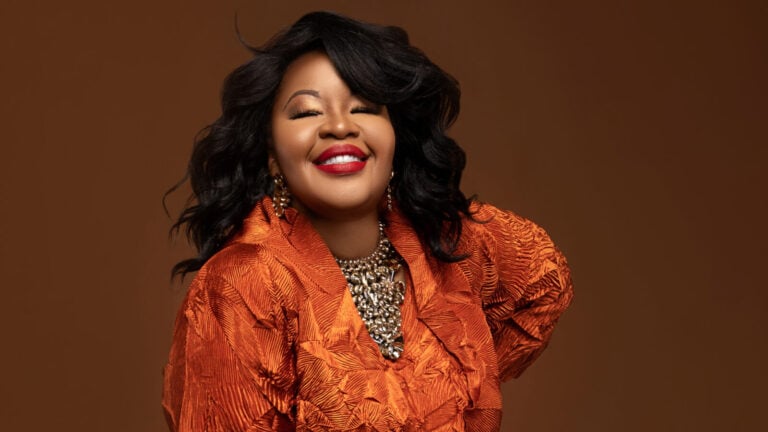 Kia Caldwell beams in a patterned orange gown
