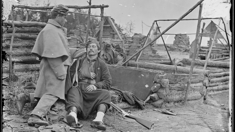 Black and white Civil War era photograph showing deserted camp and wounded soldier.