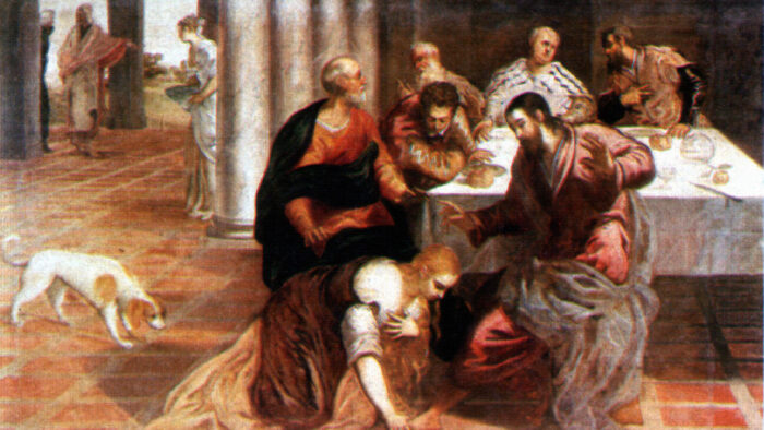 A dog watches a woman wash the foot of a man seated at a table where other men also sit. Figures, probably servants, are seen in the background.