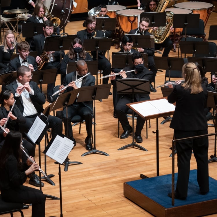 The DePaul University Wind Symphony performing on stage with conductor Erica Neidlinger