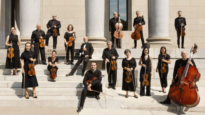 Musicians pose with instruments on grand stone steps