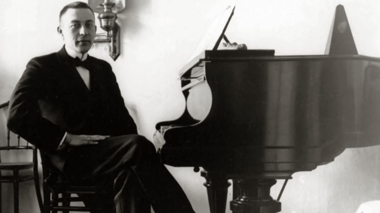 A young Rachmaninoff sits at the piano, black and white photo.