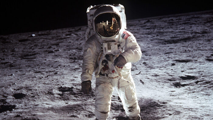man in space suit walking on moon