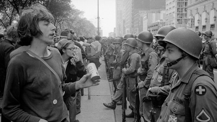 young man faces helmeted National Guardsmen