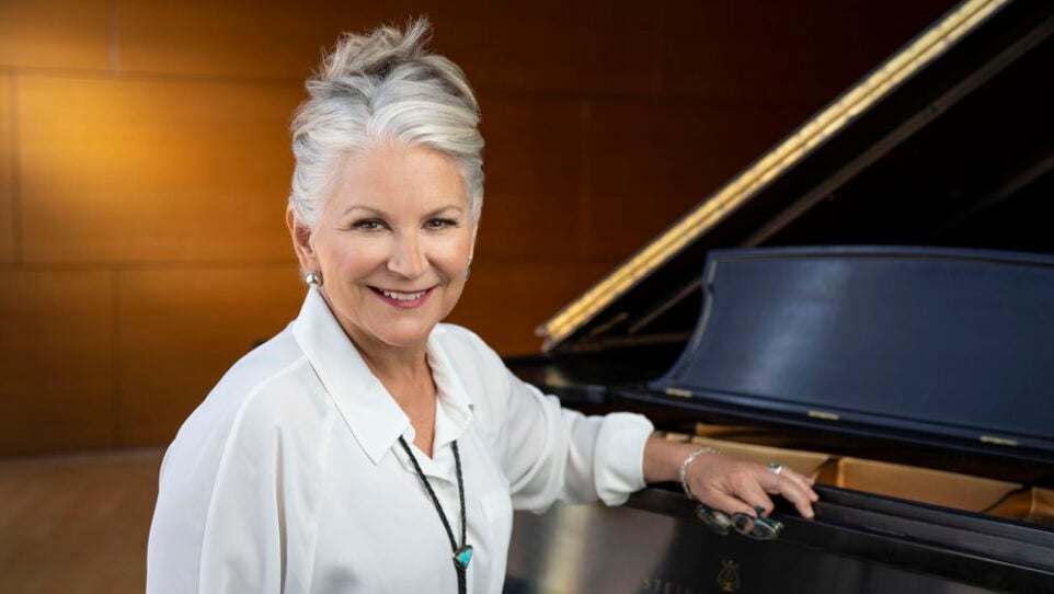 Patrice Michaels posing in front of a piano