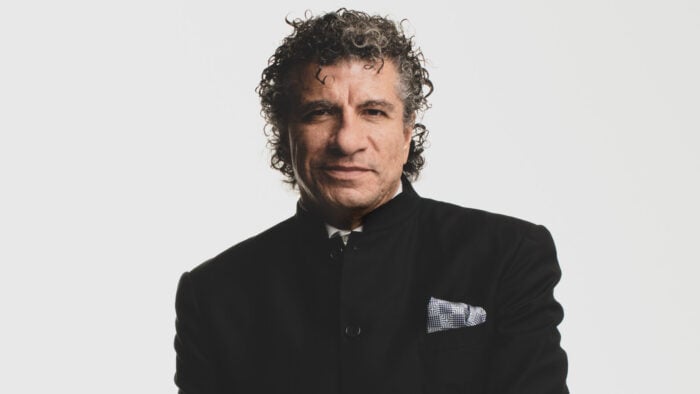 Man in dark suit poses in front of white background