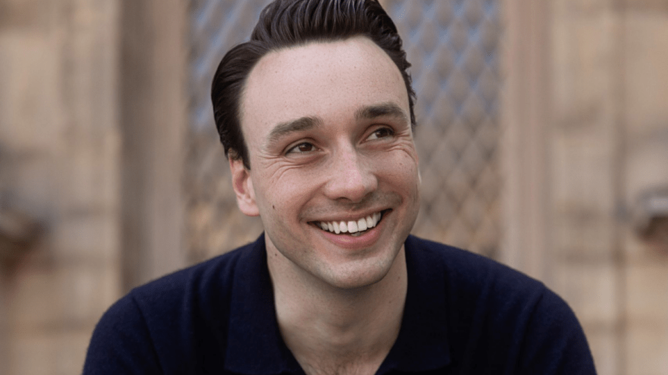 Portrait of Huw Montague Rendall smiling widely.