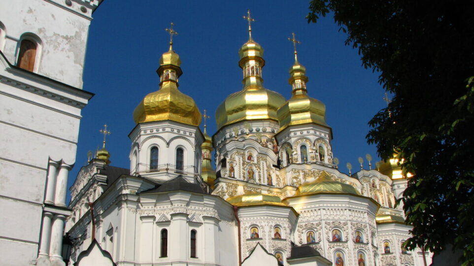 11th-century Slavonic Orthodox Church, featuring three golden-domed towers. the outside walls feature depictions of the saints.