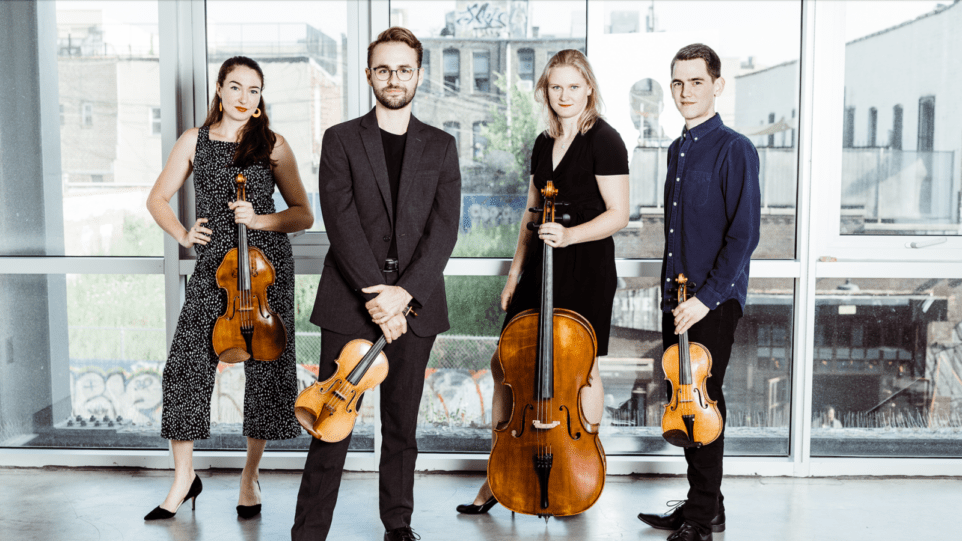 members of the Callisto Quartet posing with their instruments in front of a window