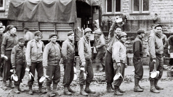 WWII soldiers in line with their mess kits