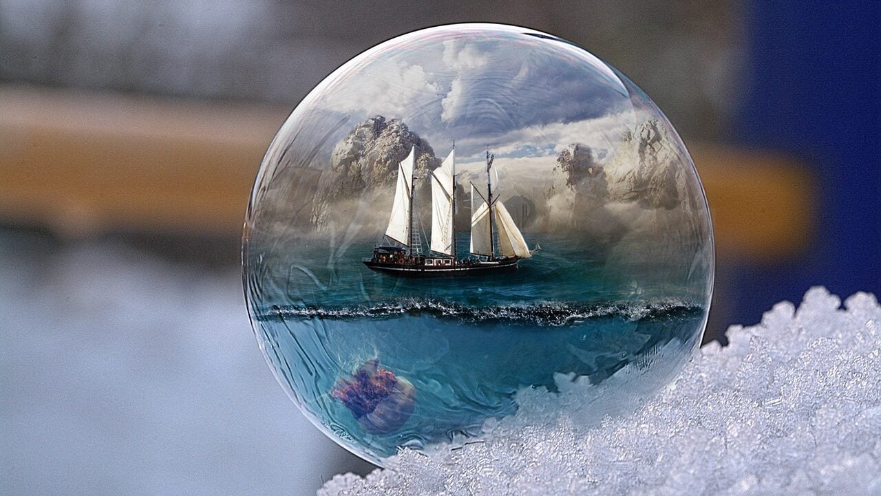 a sailing ship reflected in a glass bubble on a pile of snow