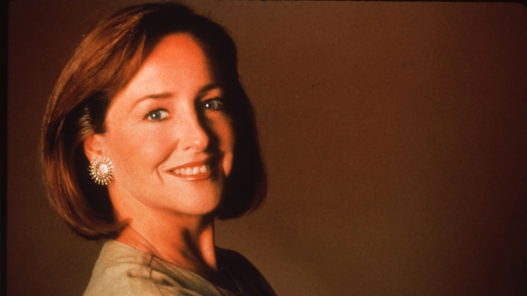 Soft focus portrait of Frederica von Stade looking over her right shoulder, chin-length hair, bronze earring in the shape of the sun.