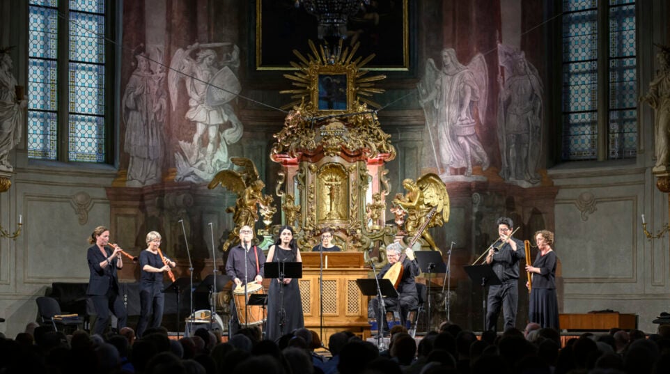 men and women in a church playing recorders, sackbut, organetto, theorbo, and tambor