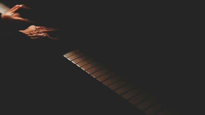 A dark shadow on a keyboard with light hitting the hands in the top left corner