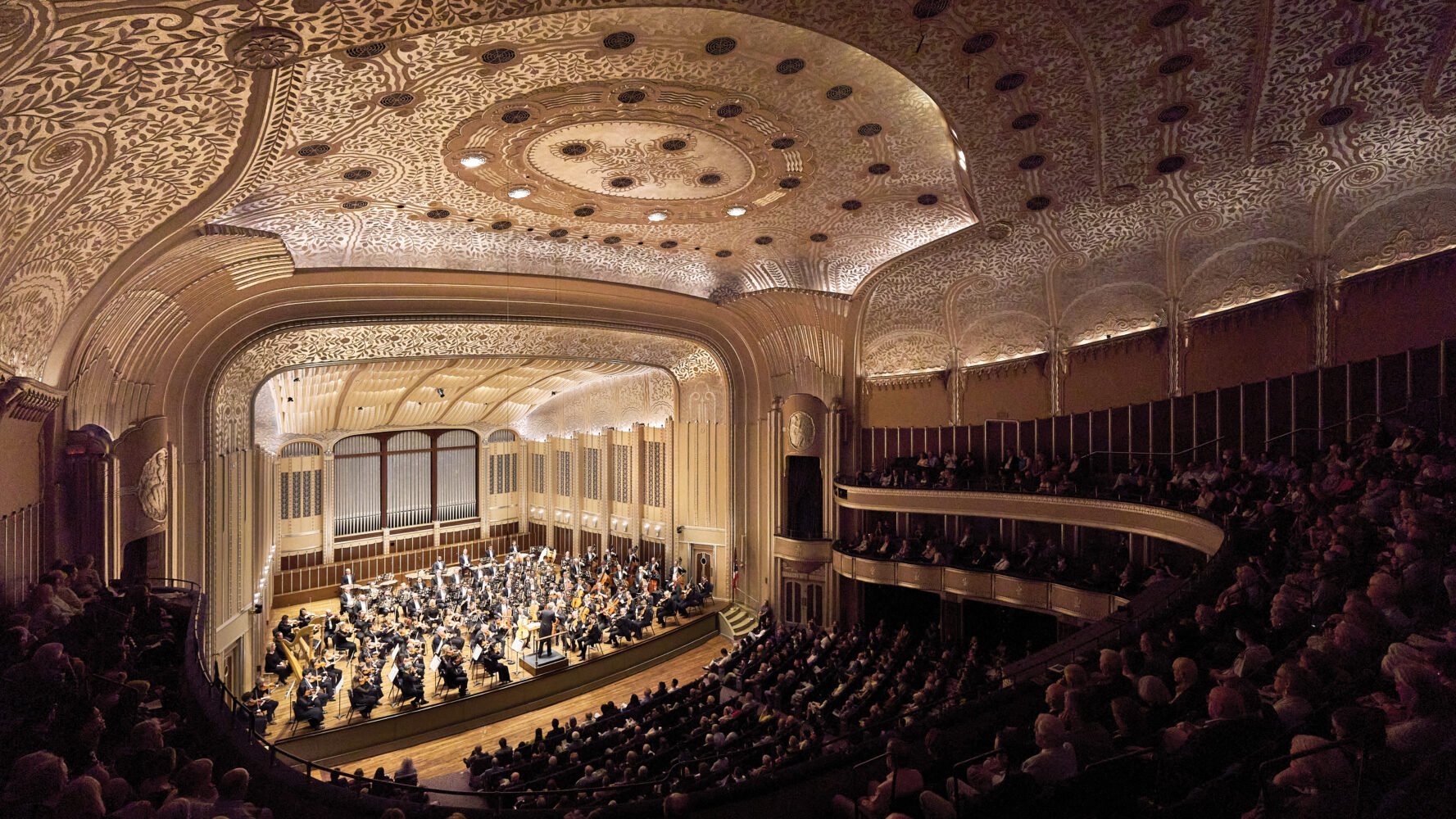 Richly adorned concert hall with full orchestra and audience