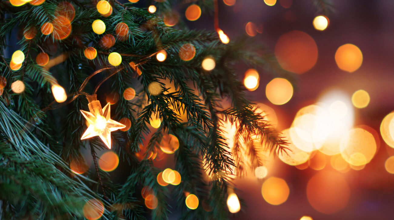 Closeup of glimmering Christmas tree with an illuminated star and golden background lights