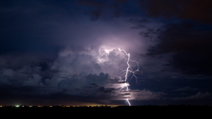 A lighting bolt knifes through a cloudy sky