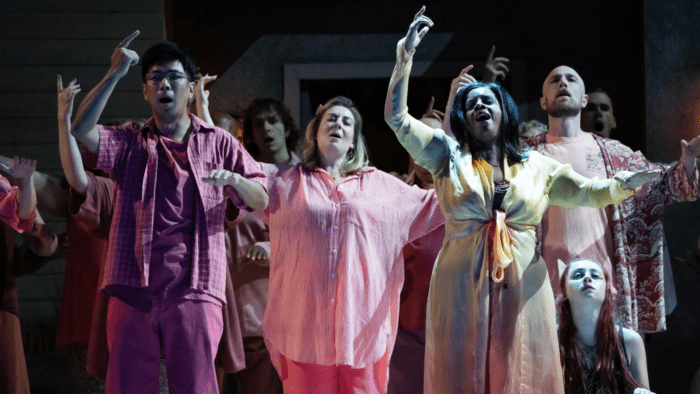 Multiple figures in pink, fuchsia, or rose colored casual attire, seeming to be dancing in a reverie with their right arms gesturing upwards.