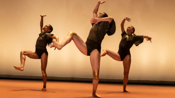 Three dancers in black in motion