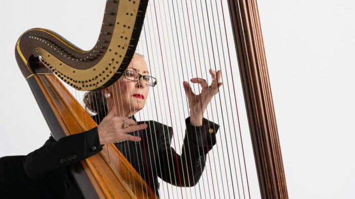 woman playing harp in front of white background